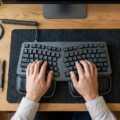 Ergonomisk tastatur placeret på et professionelt skrivebord med korrekt håndposition